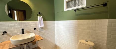 A bathroom with a white sink, wooden countertop, and a toilet.