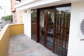 Ein Wohngebäude mit Balkon, Schiebeglasfenstern und einer sichtbaren Klimaanlage.
