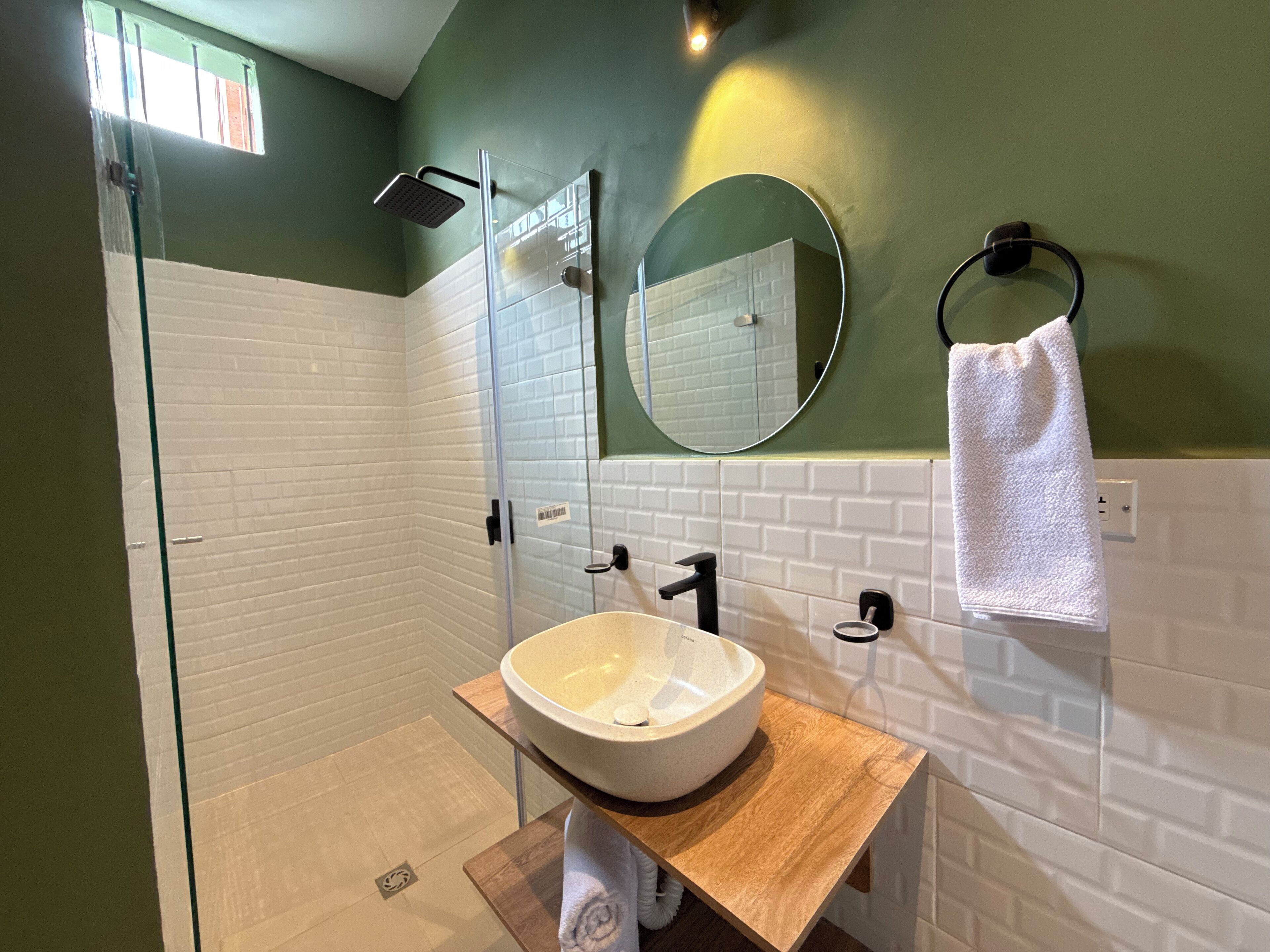 A modern bathroom with a glass shower enclosure, a white sink with a wooden countertop, and a towel hanging on a black towel ring.