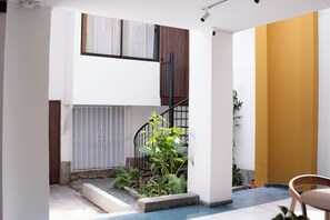 Un interior moderno con una escalera, un pequeño jardín y una pared amarilla.