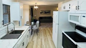 A modern kitchen with white cabinetry, a dining area with a table and chairs, and a living room in the background. - Charming 2-bedroom condo in lovely Springfield with AC (Springfield)