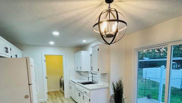 A modern kitchen with white cabinets, a glass dining table, and a large window. - Charming 2-bedroom condo in lovely Springfield with AC (Springfield)