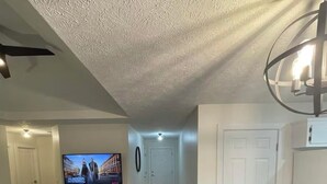 A living room with a flat-screen TV, a sofa, a coffee table, and a patterned rug. - Charming 2-bedroom condo in lovely Springfield with AC (Springfield)