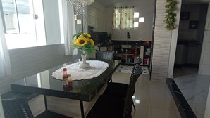 A dining area with a glass table, a vase with sunflowers, and a bottle of ketchup. - Ksl bird refuge (Araquari)