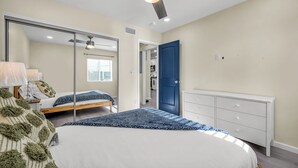 Quarto com cama, penteadeira, espelho e ventoinha no teto.