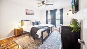 Un dormitorio con cama, mesita de noche, lámpara y ventilador de techo.