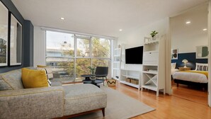 Un salon moderne avec un canapé gris, une petite table et un téléviseur.