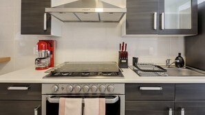 Une cuisine moderne équipée d’une cuisinière à gaz, d’un four et d’une machine à café.