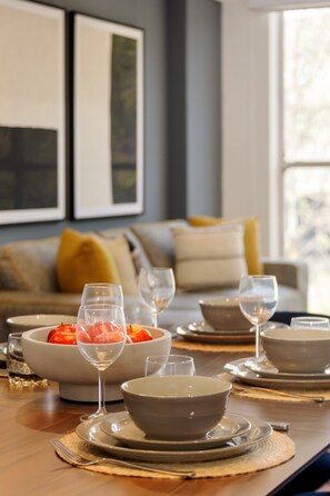 A dining table set with bowls, plates, and wine glasses, with a sofa and cushions in the background. - Cozy 2BR Apartment Steps from Reforma. (Mexico City)