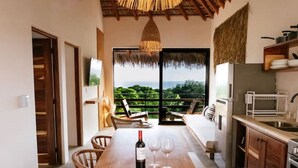 A spacious kitchen with a large wooden island, a dining area with chairs, a TV mounted on the wall, and a view of the outdoors through large windows. - Sunny 2 BR Penthouse w/ Priv. Jacuzzi & Balcony (La Barra)