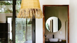 A modern kitchen with a wooden island, a hanging bamboo light fixture, and a round mirror on the wall. - 2BR Beachside Escape with Private Terrace (La Barra)