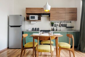 A compact kitchen with a refrigerator, microwave, and wooden cabinets. There is a dining table with chairs and a hanging light fixture above. - Cozy & Stylish 1BR Apartment W/ Balcony (Mexico City)