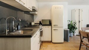 Eine moderne Küche mit Spüle aus Edelstahl, einem Herd, einer Mikrowelle und einem weißen Kühlschrank.