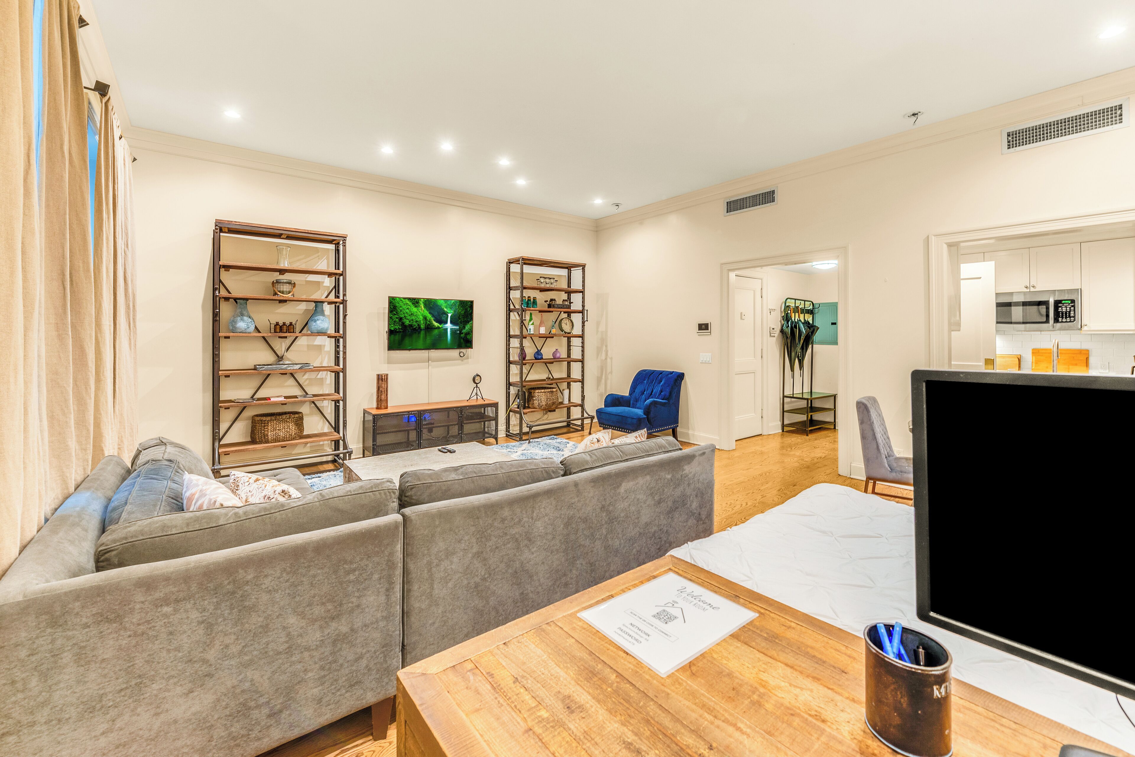 A living room with a sectional sofa, wooden coffee table, and two bookshelves filled with decorative items.