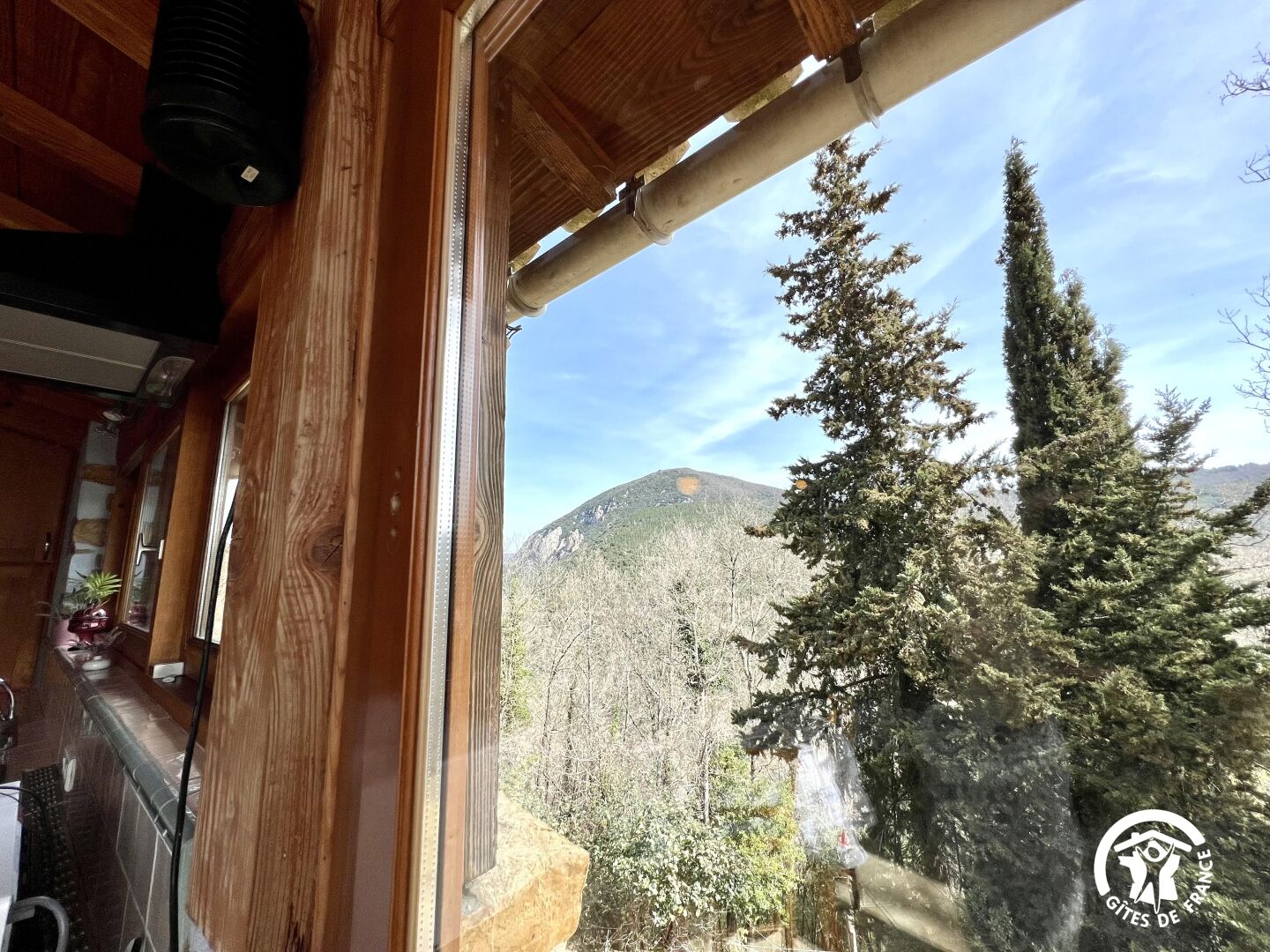 L’intérieur d’un chalet en bois, avec vue sur une forêt et une montagne.
