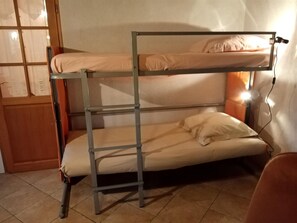 Un lit superposé avec une échelle, une table de chevet et une lampe.