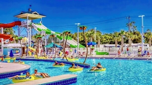 En swimmingpool med vandrutsjebaner og liggestole.