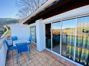 Une terrasse avec une table et des chaises, une porte-fenêtre coulissante et une vue sur la campagne.