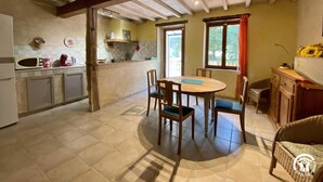 A spacious kitchen with a dining area, featuring a wooden table and chairs, a built-in oven, and a window with curtains. - Le Souleilla - SAINT JULIEN DE BRIOLA (SAINT JULIEN DE BRIOLA)