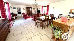 Ein geräumiges Wohnzimmer mit Essbereich, einem roten Sofa, Holzmöbeln und einer Kristallleuchtre.