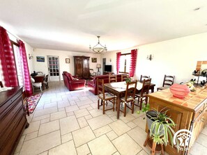 Amplia sala de estar con comedor, un sofá rojo, muebles de madera y una araña.