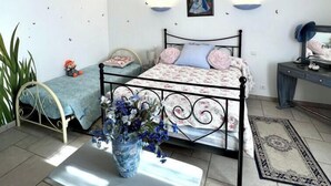 Ein Schlafzimmer mit Bett, Nachttischen, Schreibtisch, Stuhl, einer Pendelleuchte und einem Wandbild.