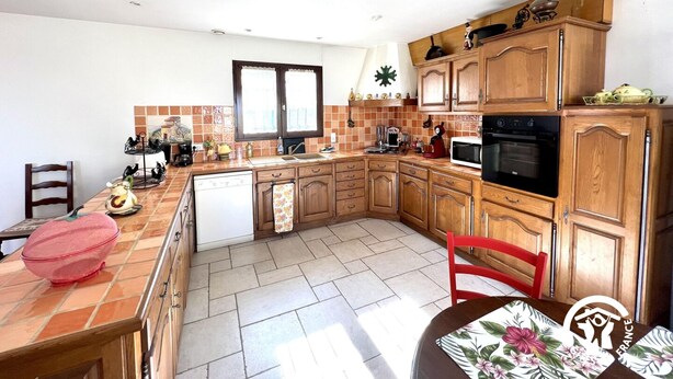Eine kleine Küche mit Holzschränken, einem eingebauten Backofen und einer gefliesten Spritzschutzwand.