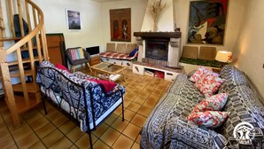 Una sala acogedora con chimenea, una escalera y un cuadro grande en la pared.