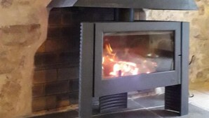 A stone wall with a modern fireplace featuring a glass front and a black chimney. - Le Vigneron - MONTGAILLARD (MONTGAILLARD)
