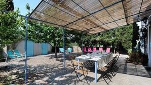 An outdoor patio with a table set for dining, surrounded by chairs and a pergola providing shade. - Le Vigneron - MONTGAILLARD (MONTGAILLARD)