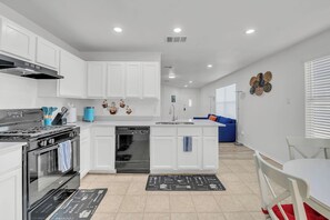 A modern kitchen with white cabinetry, a built-in oven, a dishwasher, and a central island. - Cozy Home Near Tesla COTA + Austin Airport (Austin)