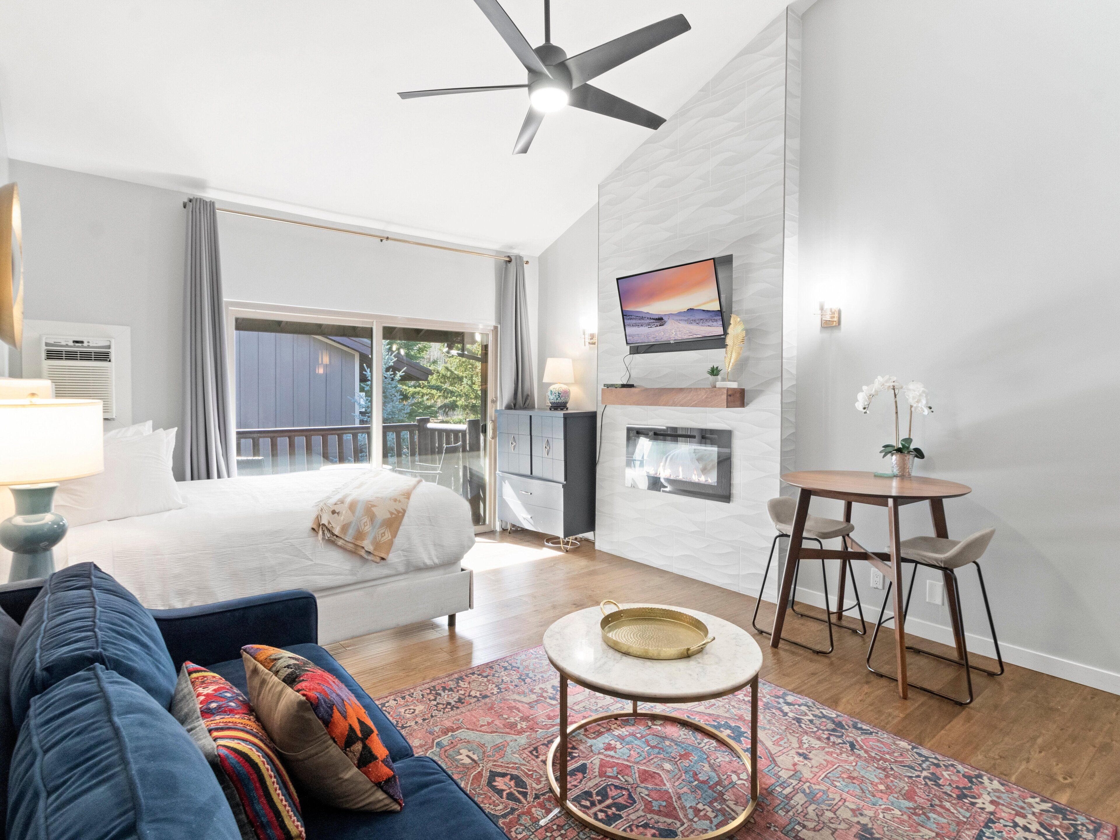 Une chambre d’hôtel moderne équipée d’un lit, d’un canapé, d’une télévision, d’une cheminée et d’un balcon avec vue.