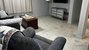 Un salon avec un canapé, une table basse, un téléviseur et une commode.