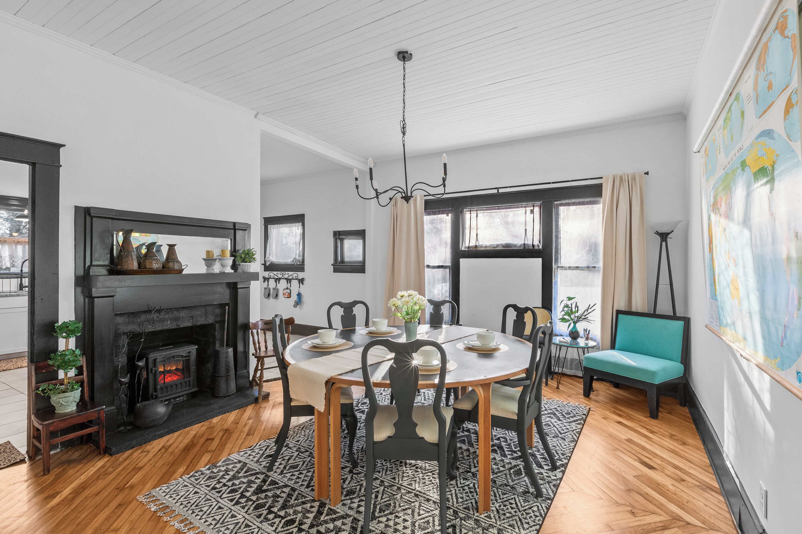 A dining room with a fireplace, round table, chairs, and a globe wall art piece.