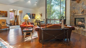 Un salon chaleureux avec une cheminée, un mur en pierre et une grande fenêtre.