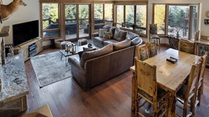 Un vaste espace de vie comprenant un grand canapé, une table à manger en bois et des chaises. On y trouve également un téléviseur et une cheminée.
