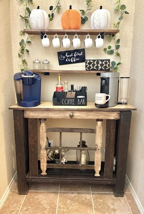 A coffee bar setup with a Keurig machine, Torani syrup, a coffee grinder, and a sign that reads 'but first... Coffee'. - Cozy and serene 4-bedroom house with AC in San Antonio (San Antonio)