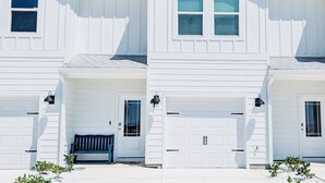 A row of white buildings with multiple garage doors and a bench in front. - Coastal Retreat Just Steps From the Beach 🌴 (Port St. Joe)