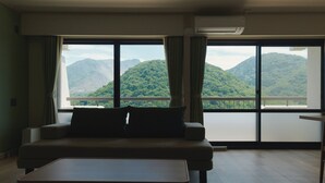 Ein Zimmer mit einer Couch, einem Couchtisch und einem großen Fenster mit Vorhängen.