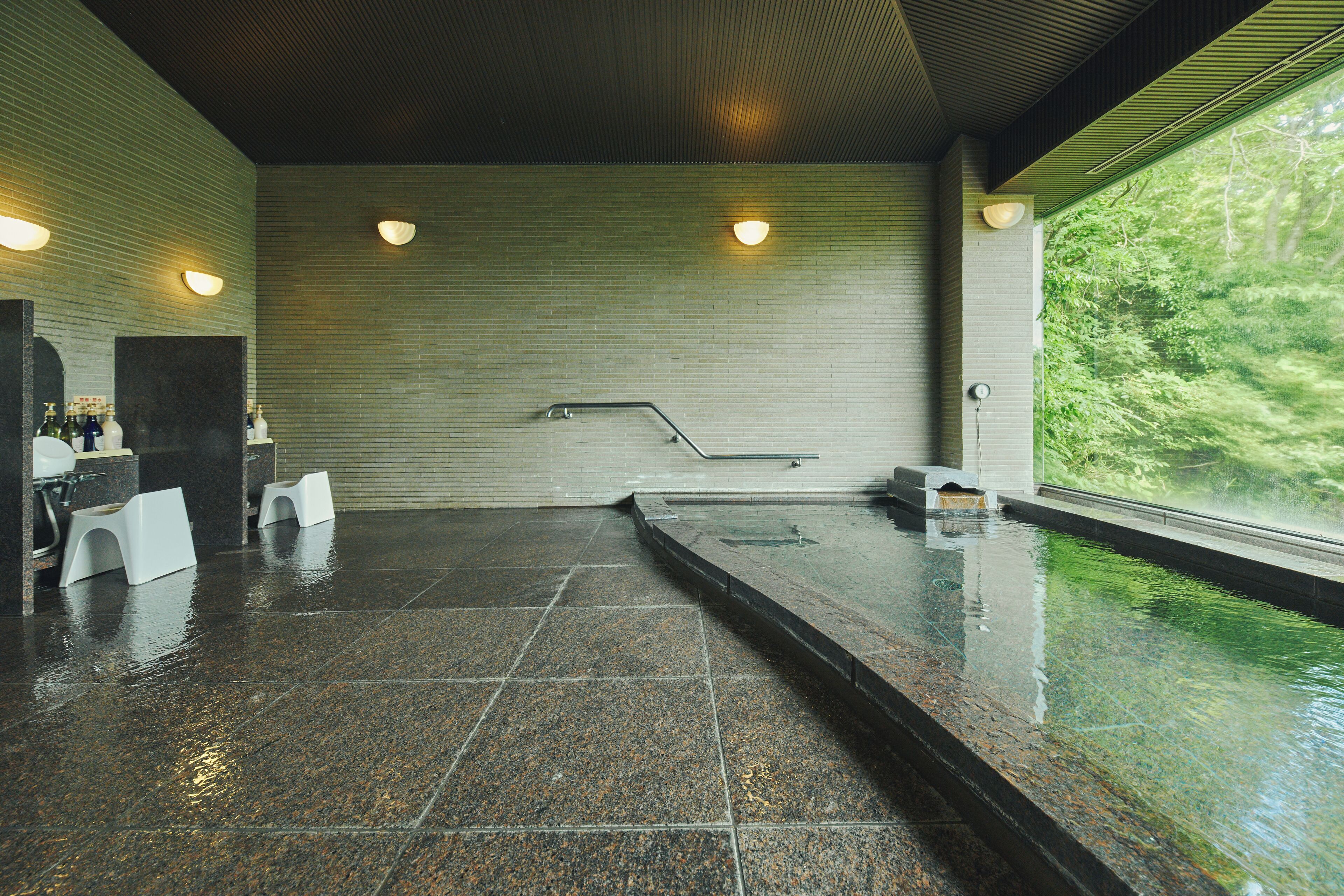 A spa area with a hot tub, seating, and a view of greenery.