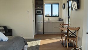 A compact bedroom with a bed, a small kitchenette, and a view of the outdoors. - Katelyn Studio  - Rural Couples Retreat (Kinloch)