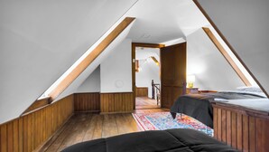 Een slaapkamer met een schuine kap, houten wanden, een bed en een nachtkastje.