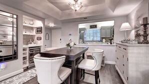 A modern kitchen with a dark wooden island, white chairs, and a chandelier. - Luxury 2-bedroom townhome on Biltmore golf course, close to dining and shopping! (Phoenix)