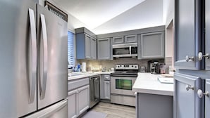 A modern kitchen with stainless steel appliances, grey cabinetry, and a white countertop. - Luxury 2-bedroom townhome on Biltmore golf course, close to dining and shopping! (Phoenix)