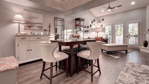 A spacious living room with a large window, a ceiling fan, and a dining area with a wooden table and chairs. - Luxury 2-bedroom townhome on Biltmore golf course, close to dining and shopping! (Phoenix)