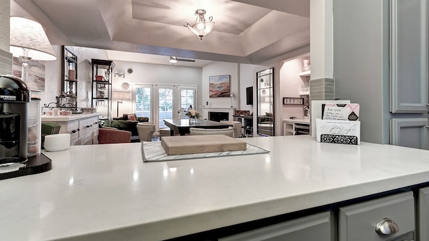 A modern kitchen with a white countertop, a coffee machine, and a dining area with a table and chairs. - Luxury 2-bedroom townhome on Biltmore golf course, close to dining and shopping! (Phoenix)