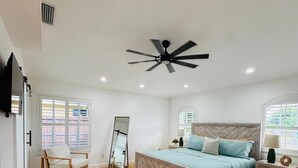 A bedroom with a bed, a chair, a ceiling fan, and a window. - 3-bedroom house in fantastic Marco Island with AC (Marco Island)