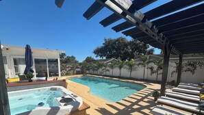 A backyard with a hot tub, a swimming pool, and lounge chairs. - NEW!! Rare 5 bedroom house w FREE HEATED POOL & HOT TUB 9 minutes to the beach!! (Seminole)