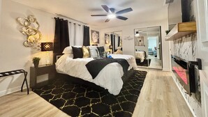 A modern bedroom with a bed, bedside tables, a ceiling fan, and a mirror. - NEW!! Rare 5 bedroom house w FREE HEATED POOL & HOT TUB 9 minutes to the beach!! (Seminole)