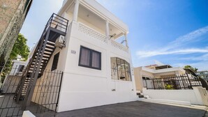 A two-story building with a balcony, a staircase, and a gated entrance. - Casa Luma No. 4 | Modern 2 Bedroom in San Juan PR (San Juan)